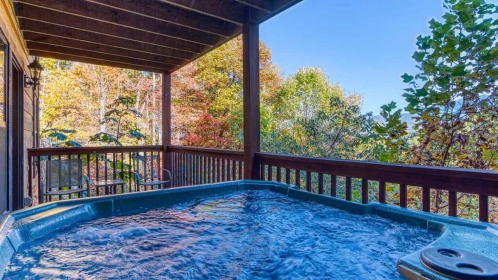 wooden cabin view on smoky mountain trees with hot tub in the foreground