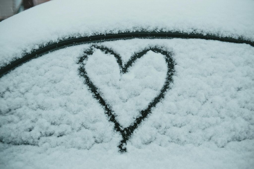 Heart painted on snowy car in winter