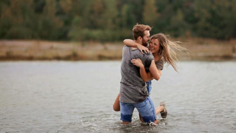 Man Hugging Laughing Woman While Standing in Body of Water