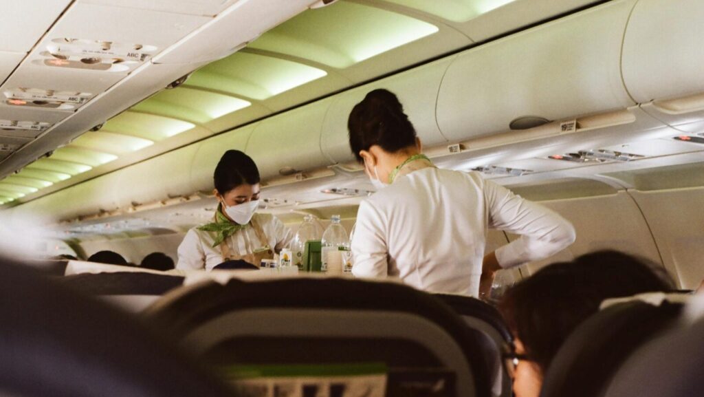 Flight Attendants Wearing Face Mask while Standing on the Aisle of an Airplane