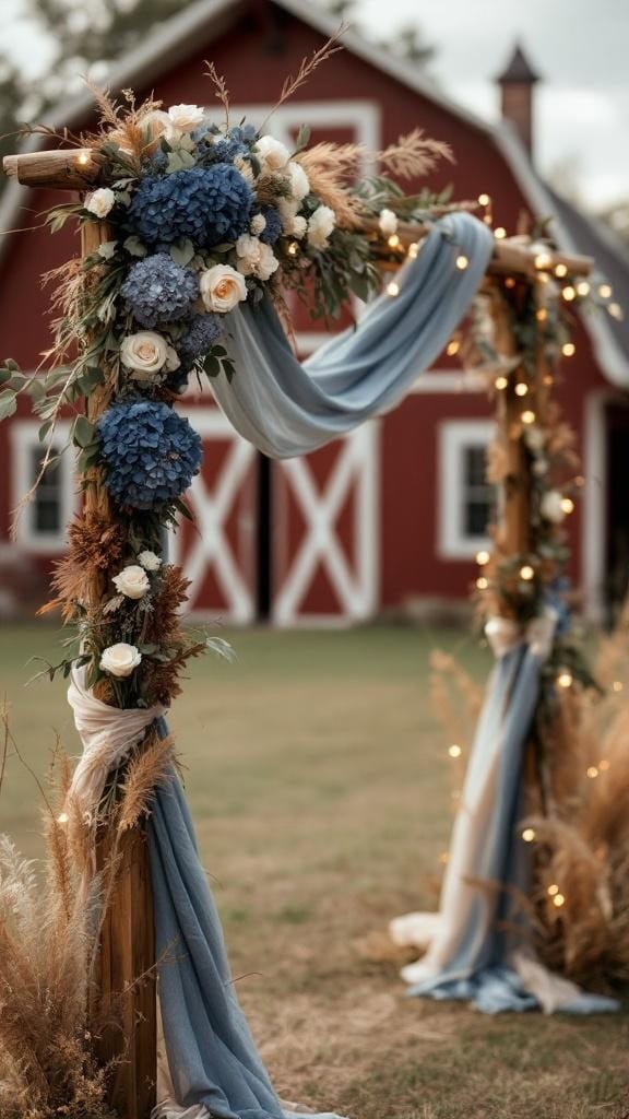 Wedding arch draped in dusty blue and beige with navy florals, set against a red barn.