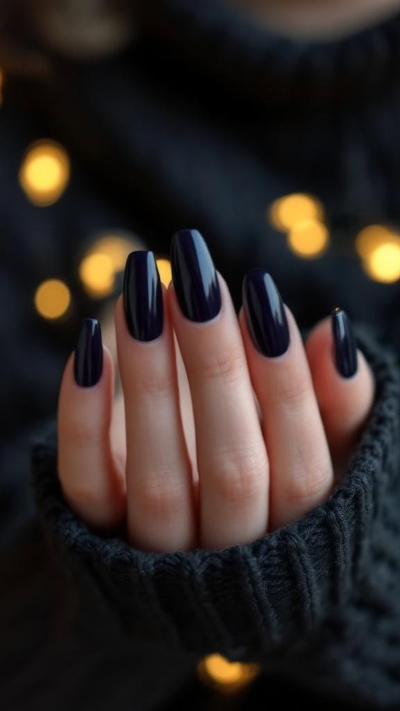 Close-up of hands with glossy midnight navy blue nails, wearing a dark sweater.