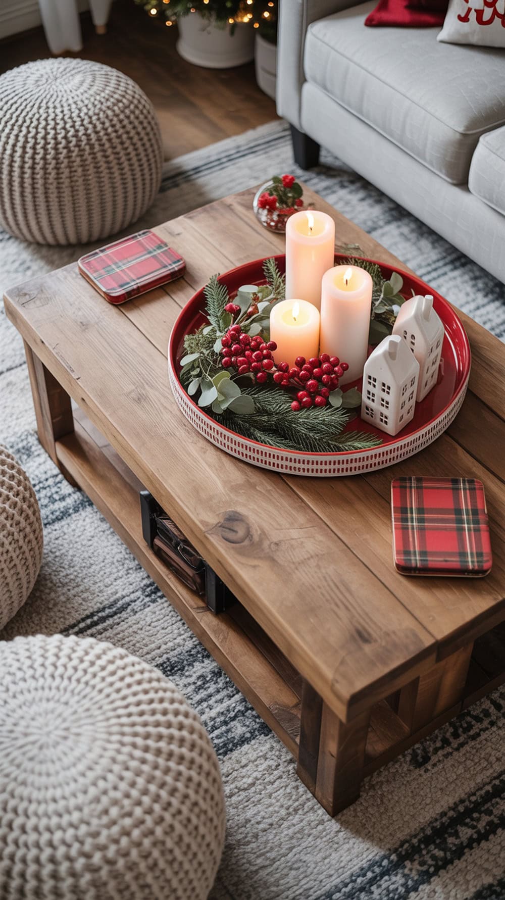 A cozy Christmas coffee table styled with red and white decor, featuring candles, greenery, and festive coasters.