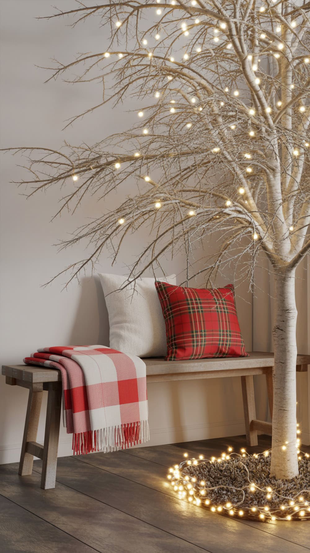 A cozy farmhouse bench with a red and white plaid blanket and pillow, next to a lit tree, creating a festive atmosphere.