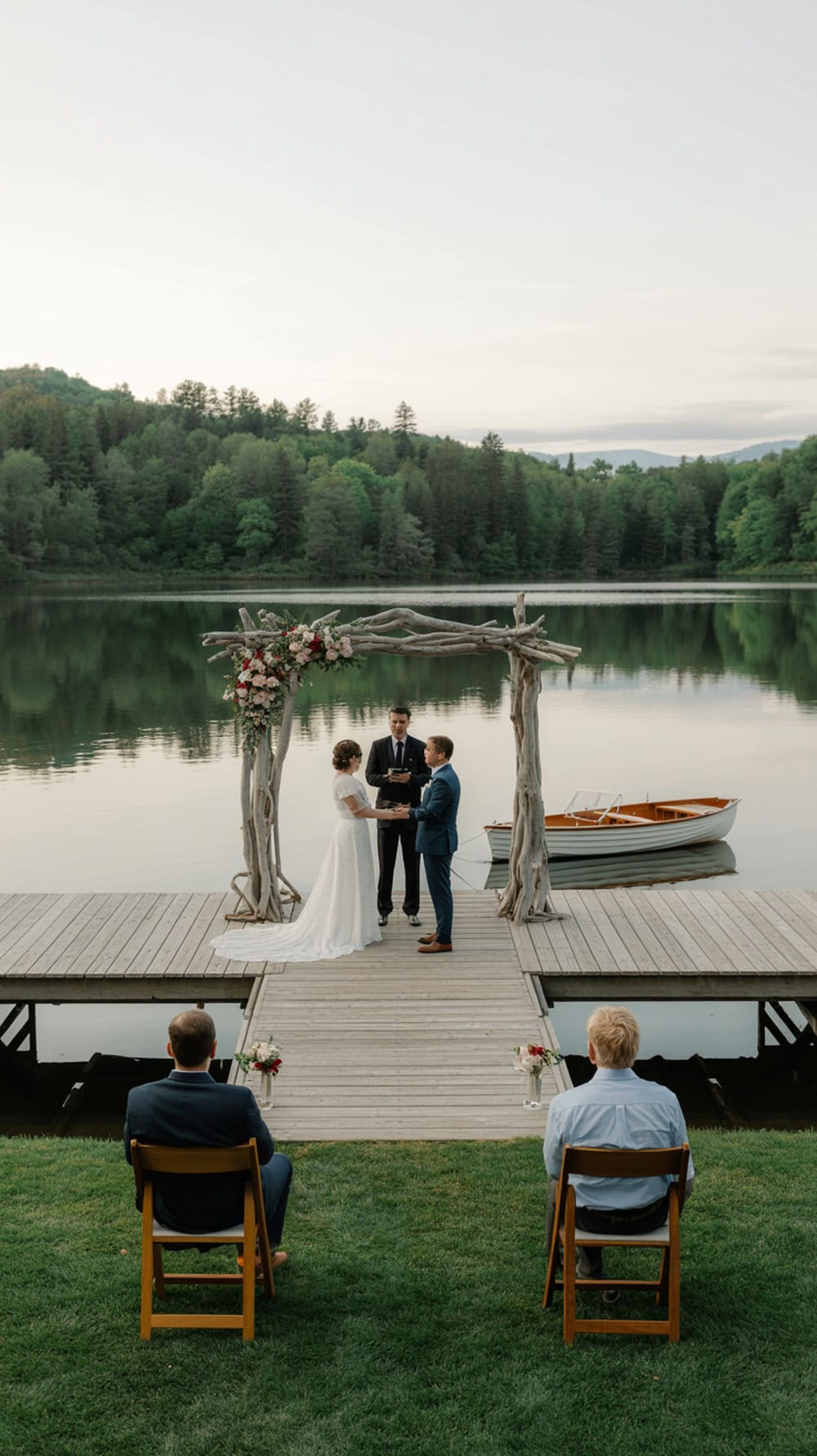 A couple getting married on a dock by a lake, surrounded by greenery and a small boat.