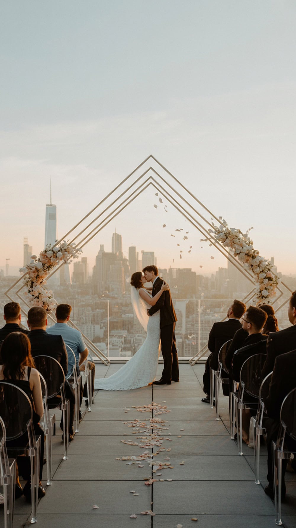 Couple kissing at a minimalist rooftop wedding with a city skyline in the background