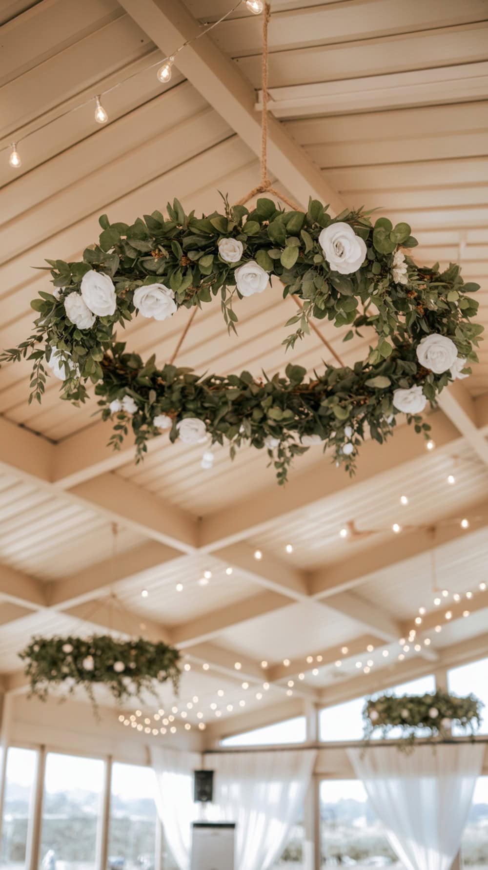 Hanging faux flower wreaths with white roses and greenery in a wedding venue