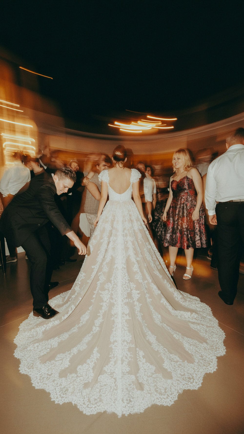 A bride with a long train dancing at her wedding reception.
