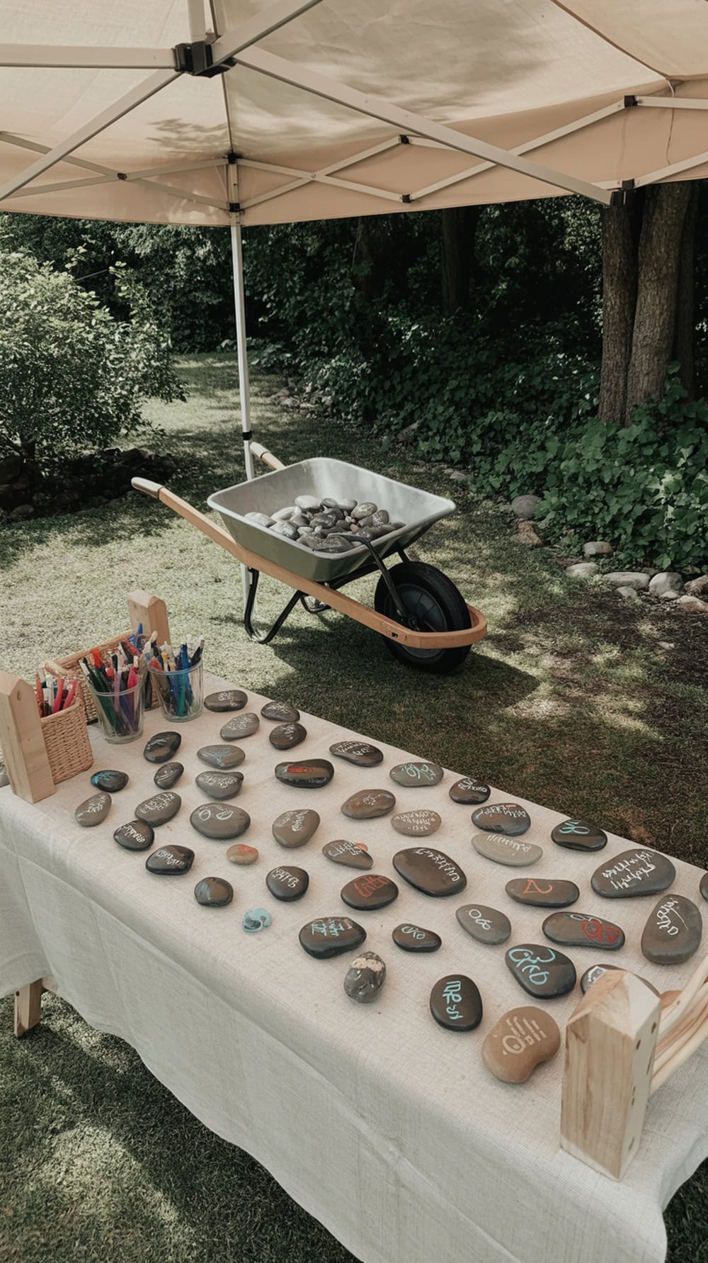 A table set up for painting rocks with colorful markers and smooth stones in a garden setting.