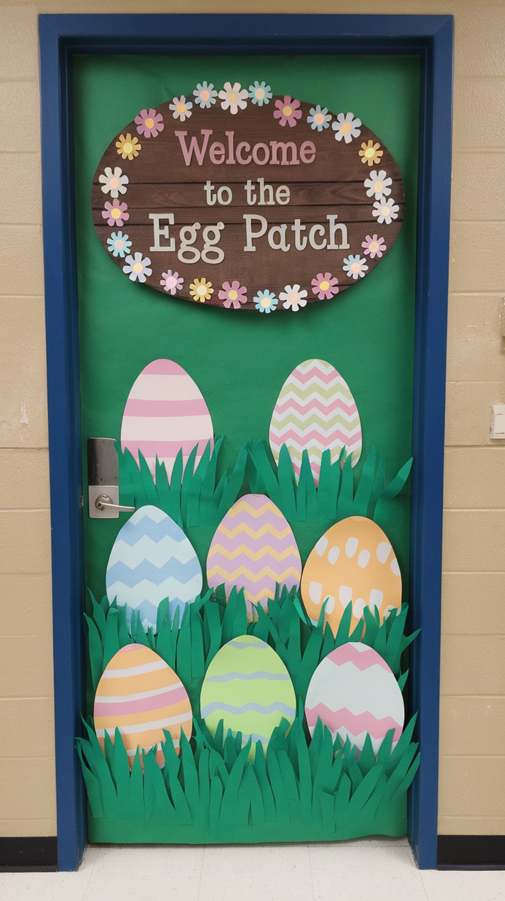 A classroom door decorated with colorful Easter eggs and a sign that says 'Welcome to the Egg Patch.'