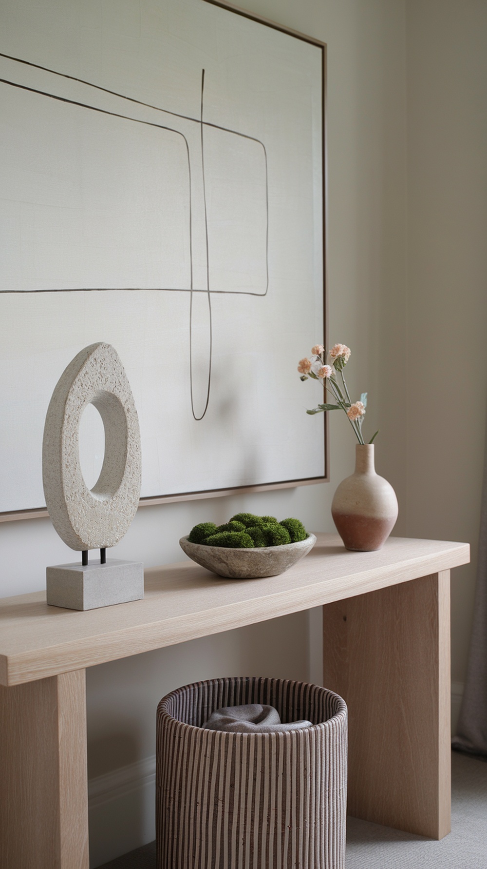 A styled console table featuring moss, stone decor, and a vase with flowers.