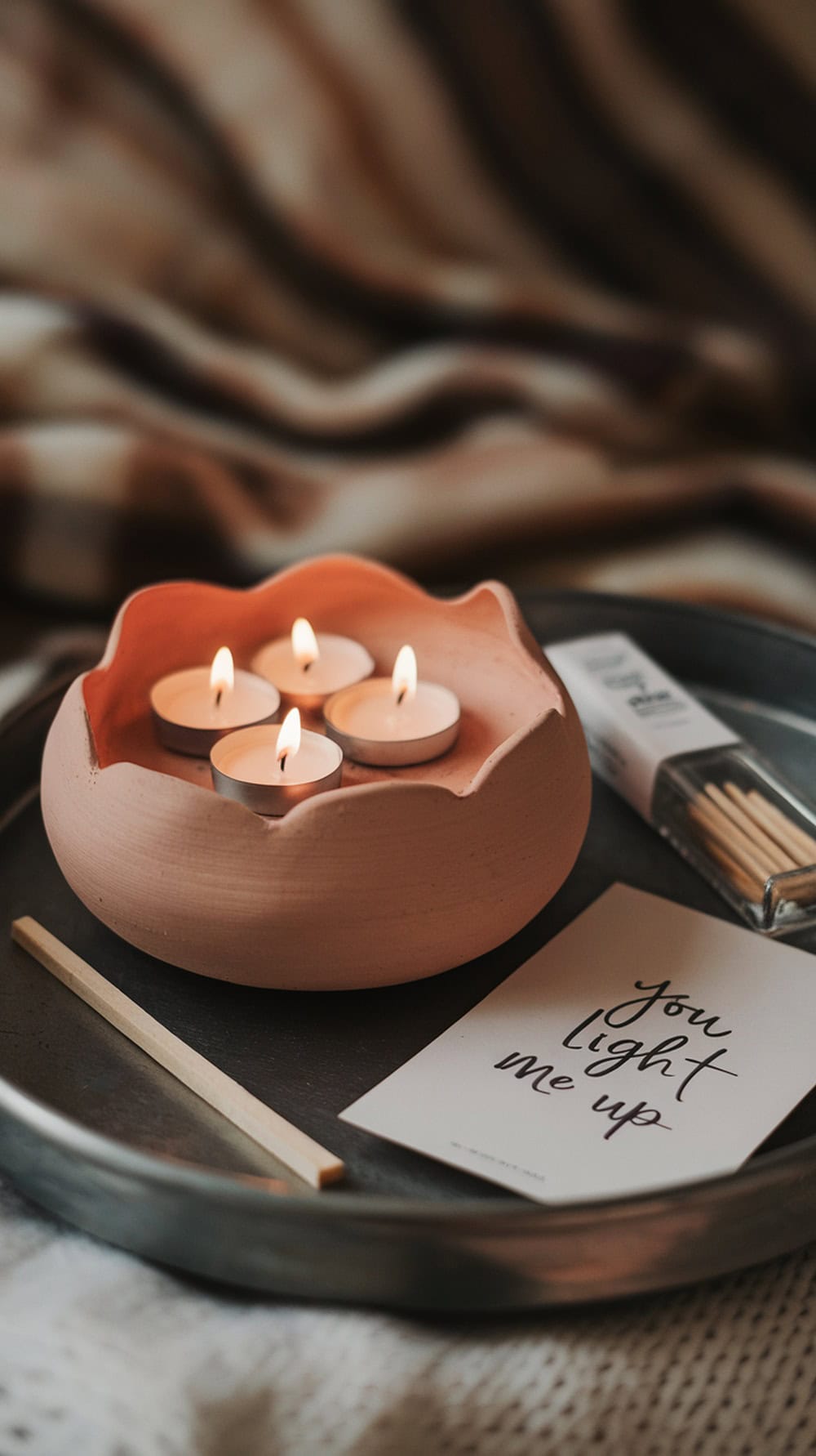 Handmade clay tea light holder with candles and a card on a tray