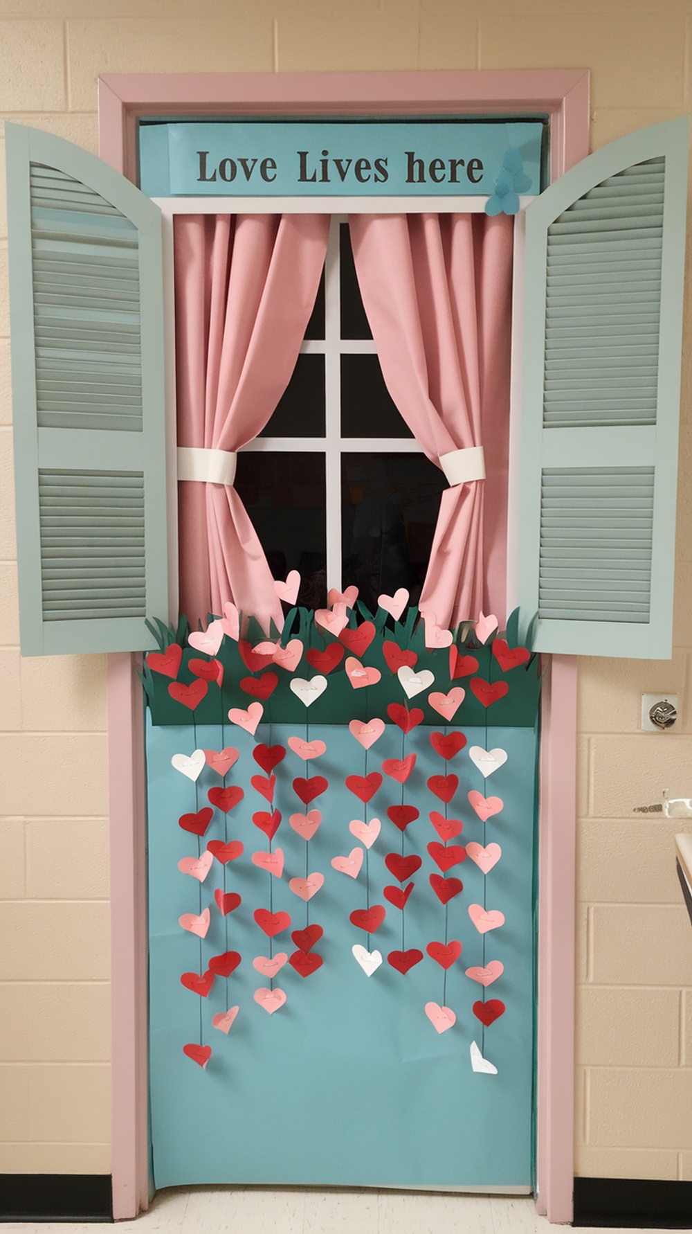 A decorated classroom door with a window design, featuring pink curtains and hanging paper hearts.
