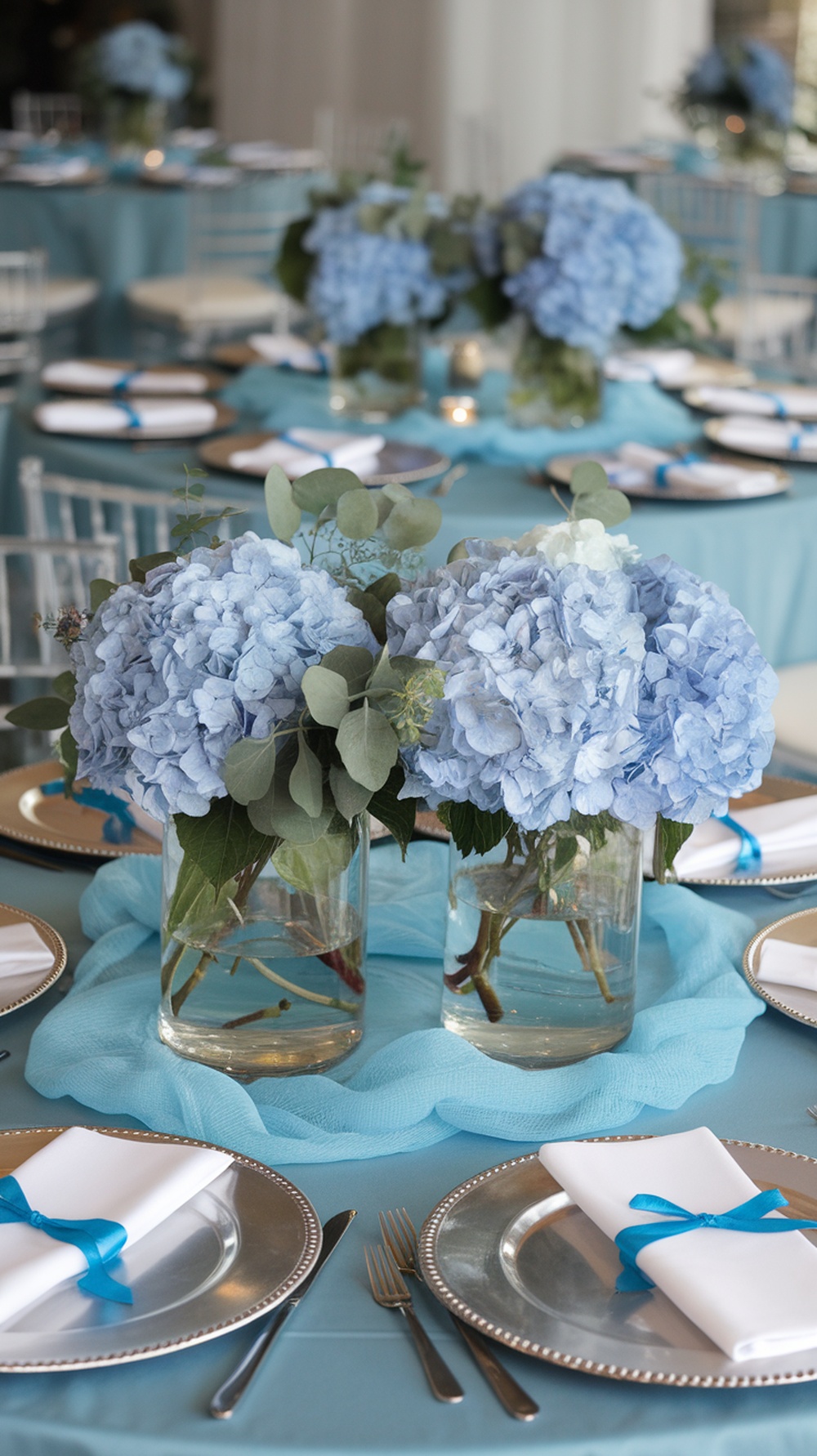 A beautifully arranged table with blue hydrangea centerpieces, elegant place settings, and a light blue table runner.