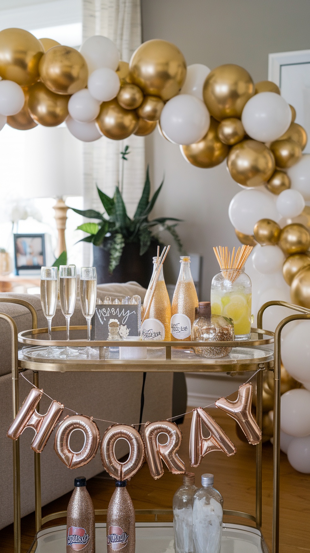 A stylish cocktail corner with a gold and white balloon arch, champagne flutes, and a sign that says 'Sip Sip Hooray'.