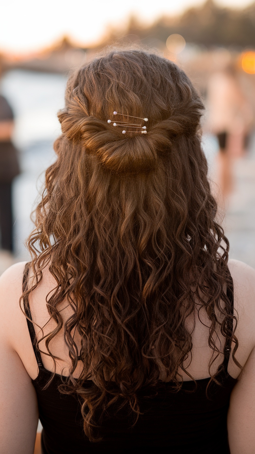 A woman with curly hair styled in a low knot half up with romantic curls, showcasing a beach wedding look.