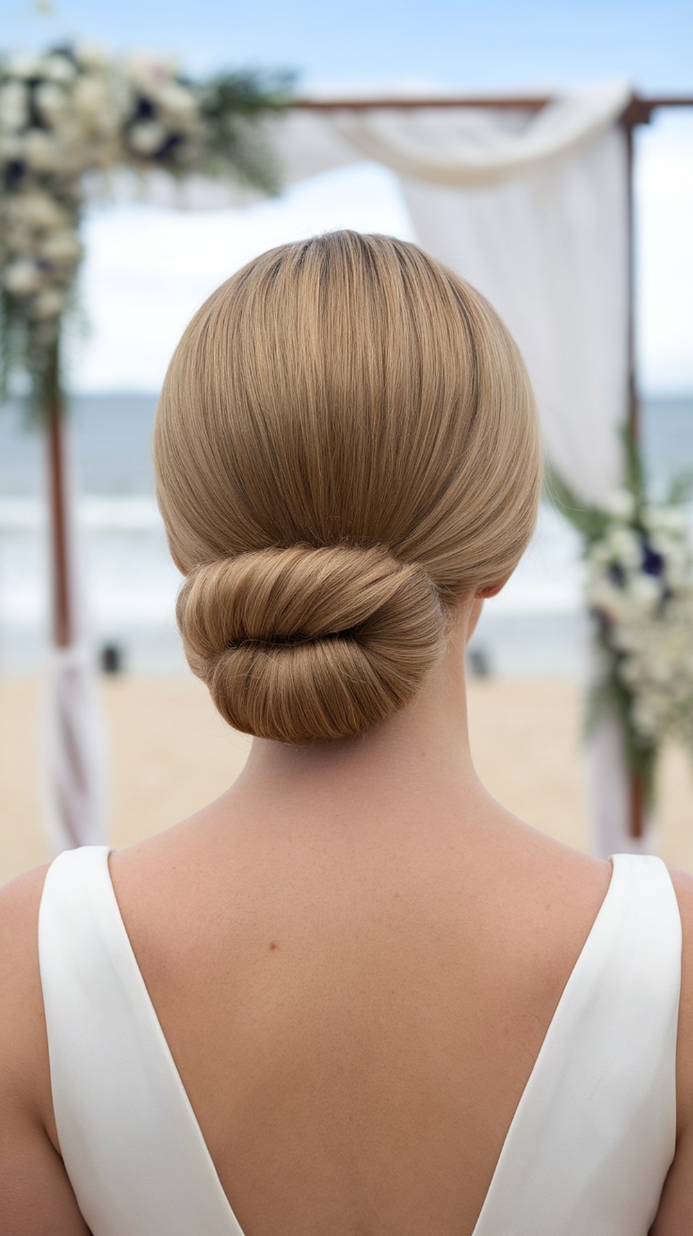 A low chignon hairstyle with loose front pieces, ideal for a beach wedding.