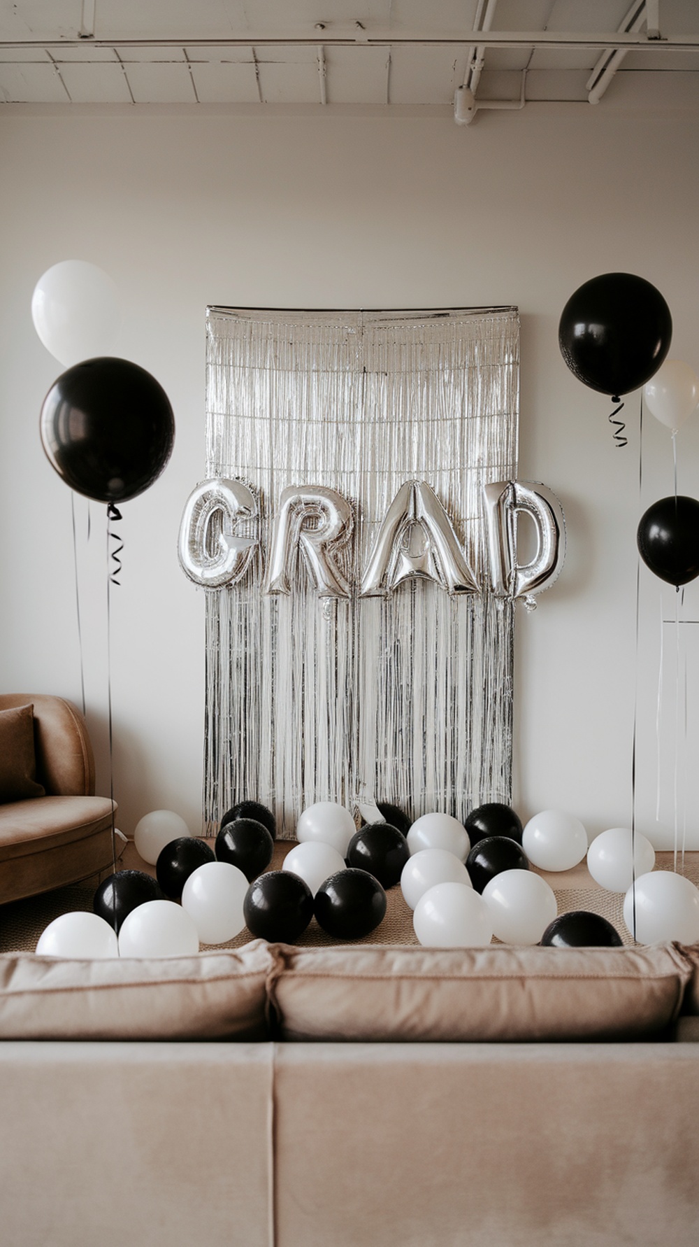A modern black and white graduation party setup with balloons and a shiny backdrop.