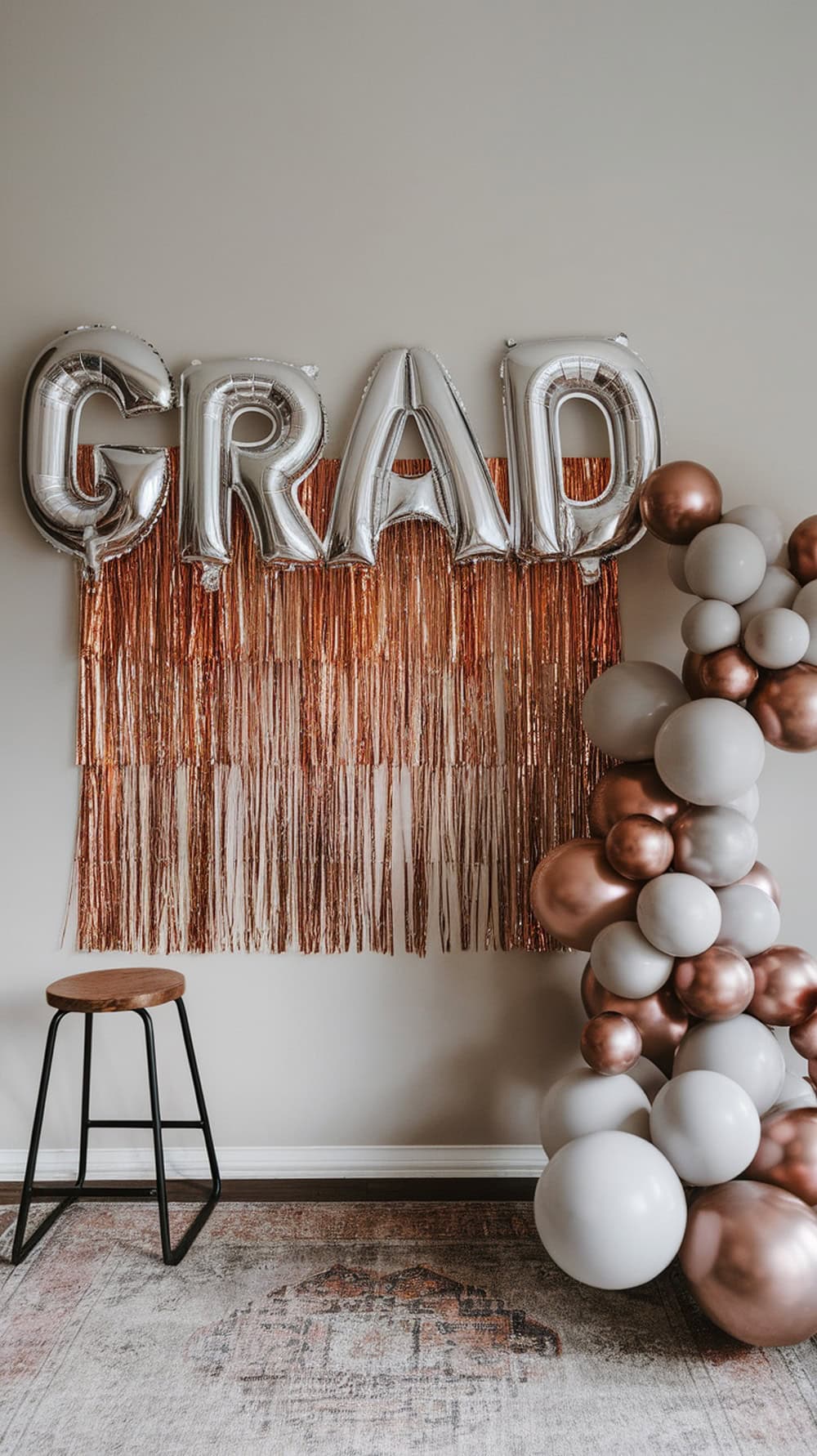 A living room photo backdrop with silver balloons spelling 'GRAD', a shiny fringe curtain, and a cluster of balloons.