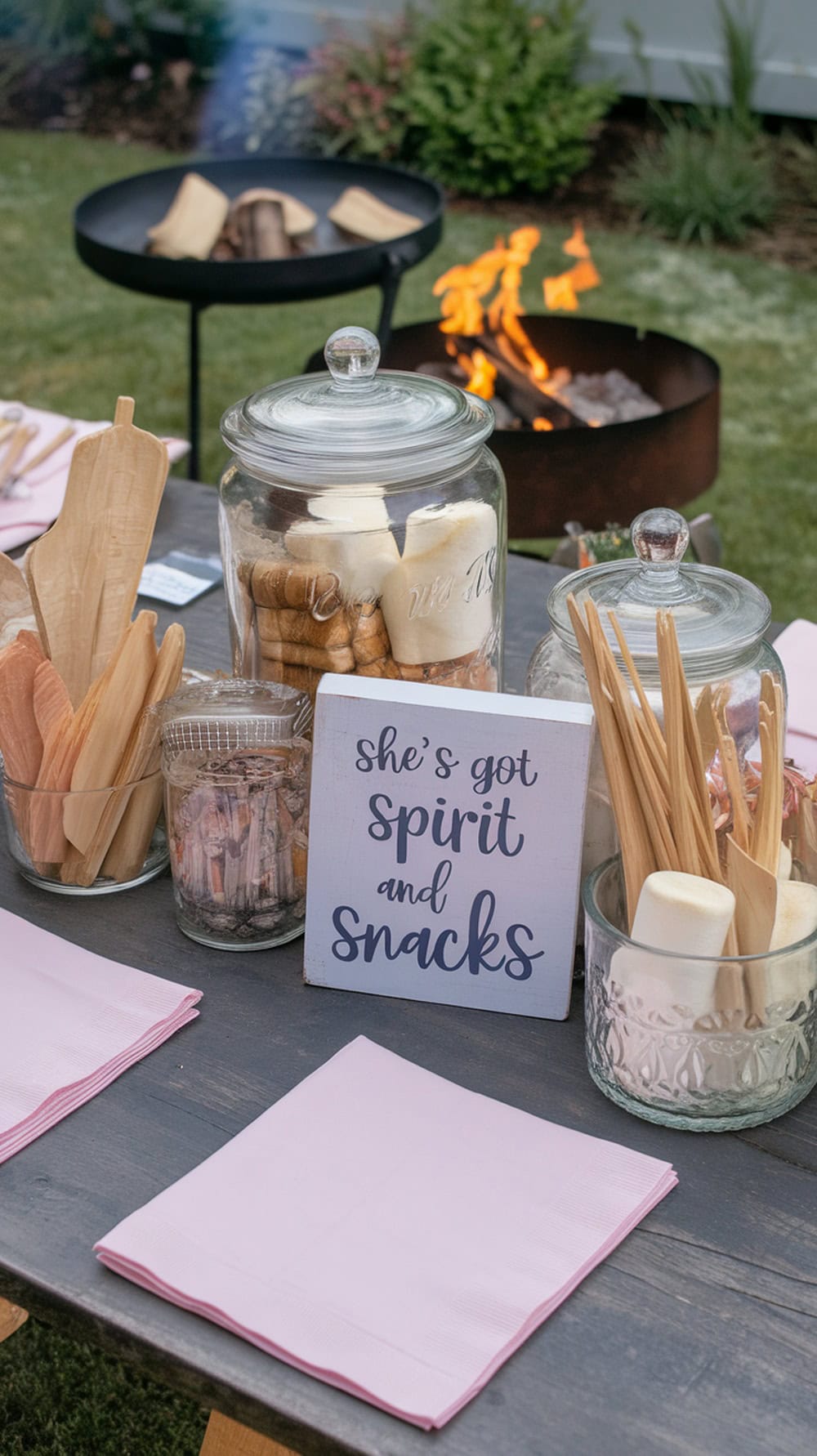 A cozy S'mores bar setup with a fire pit, colorful ingredients, and cheer-themed decorations.